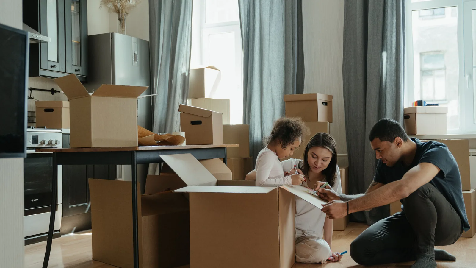 A family unpacking moving boxes together on the floor of their new home